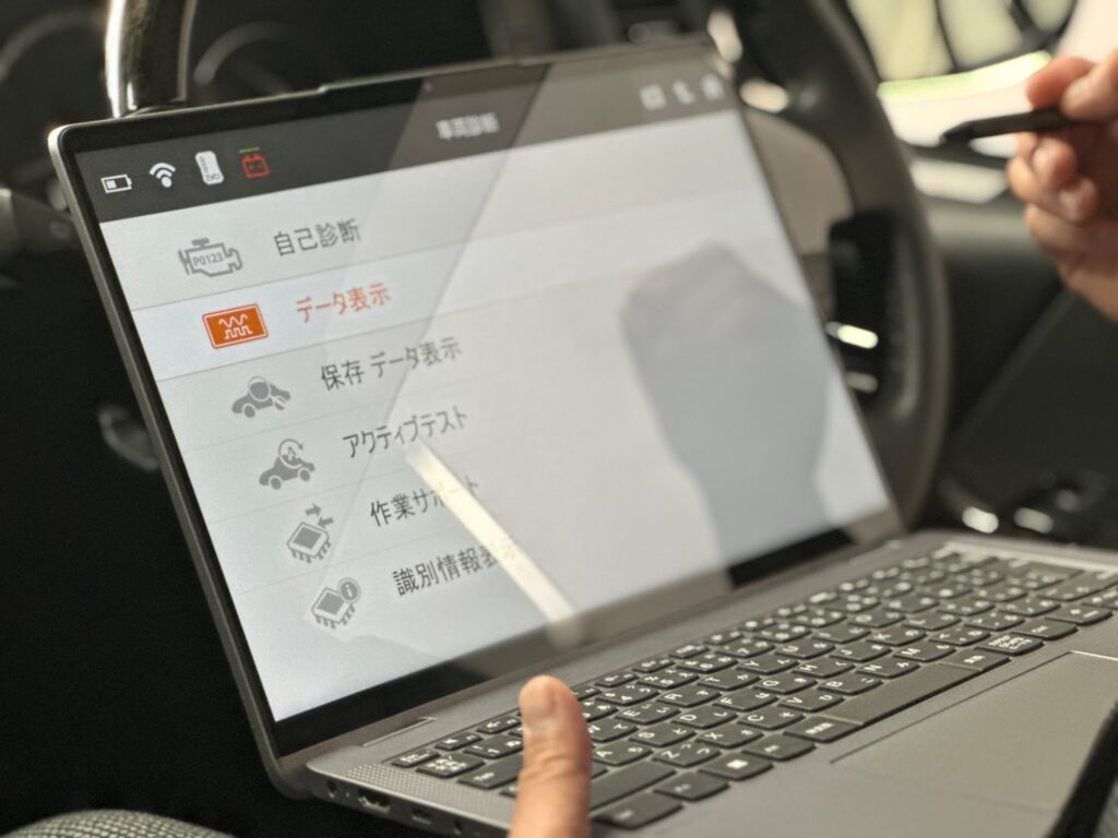 スキャンツールを操作してアクティブテストを行う整備士の手元の様子
