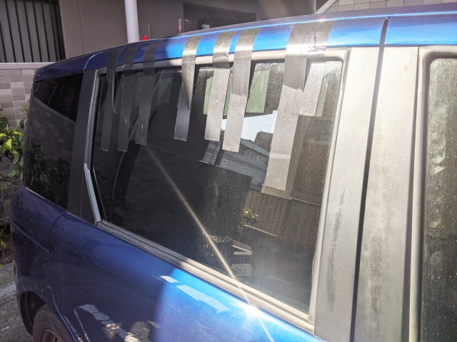 ビニールテープで窓を応急処置した故障車の側面写真