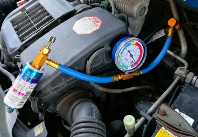 自動車のエアコンガスを注入している整備士の作業風景（HFC-134aからR-1234yfへの交換）